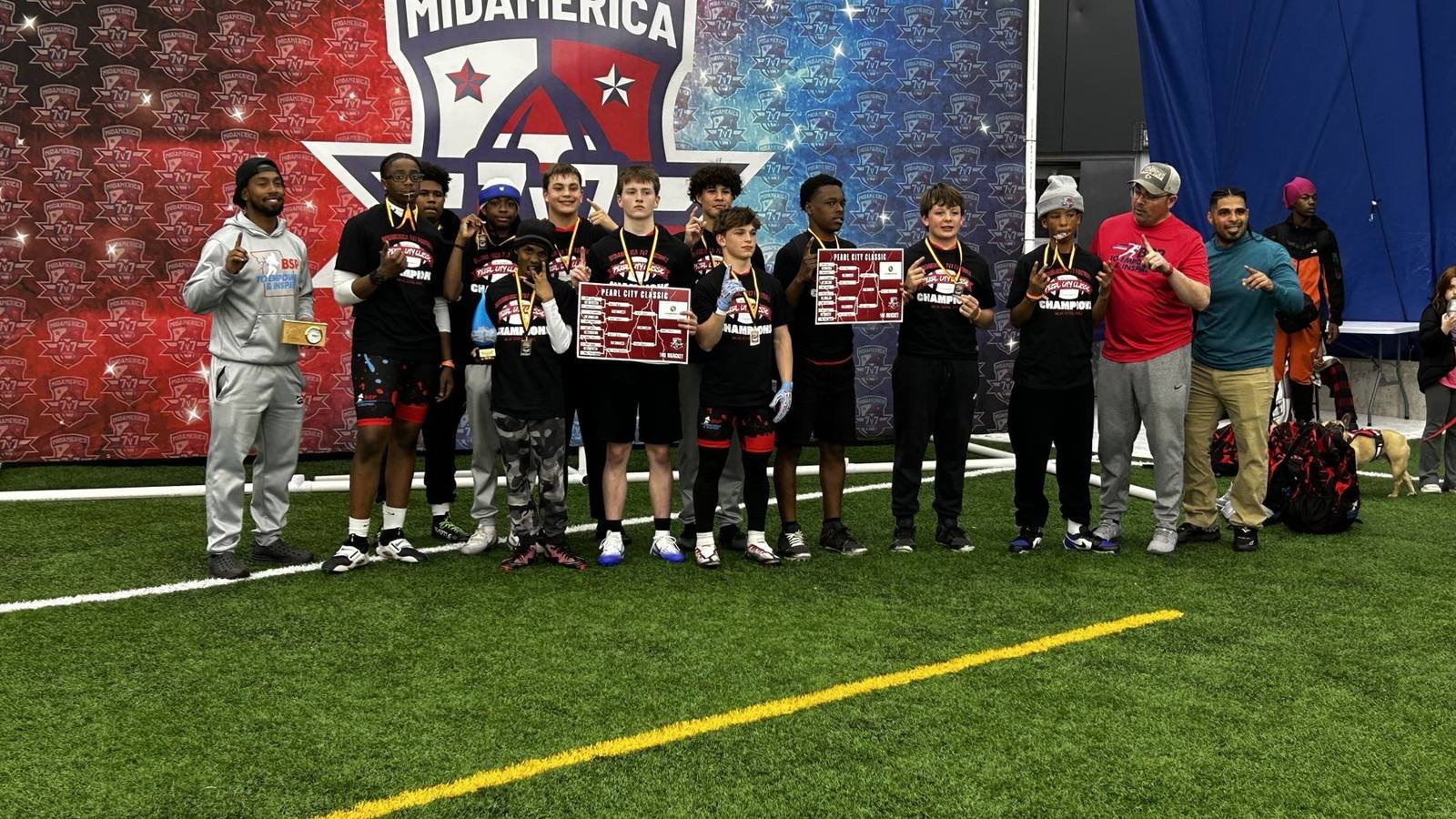 BSP older-division team in champion shirts holding two bracket boards in front of the MidAmerica 7v7 backdrop