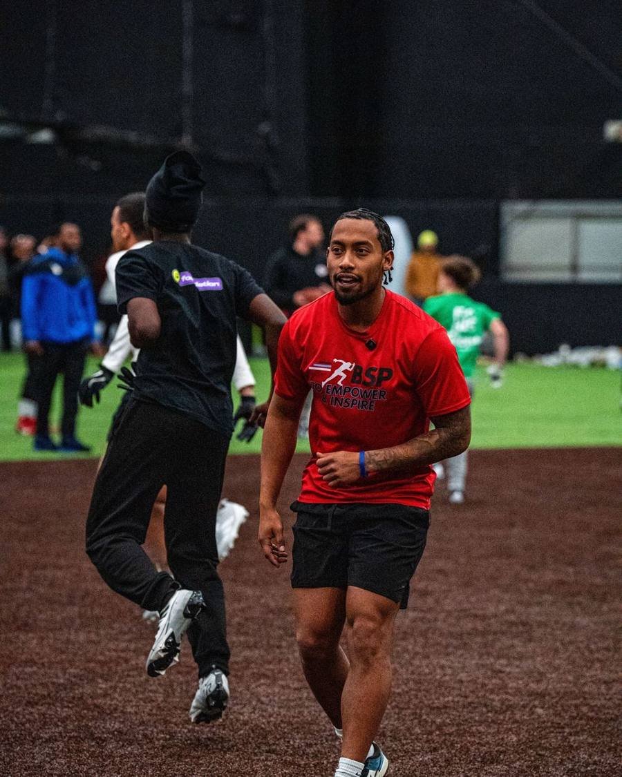 BSP coach in a red To Empower and Inspire shirt jogging across an indoor field during a session