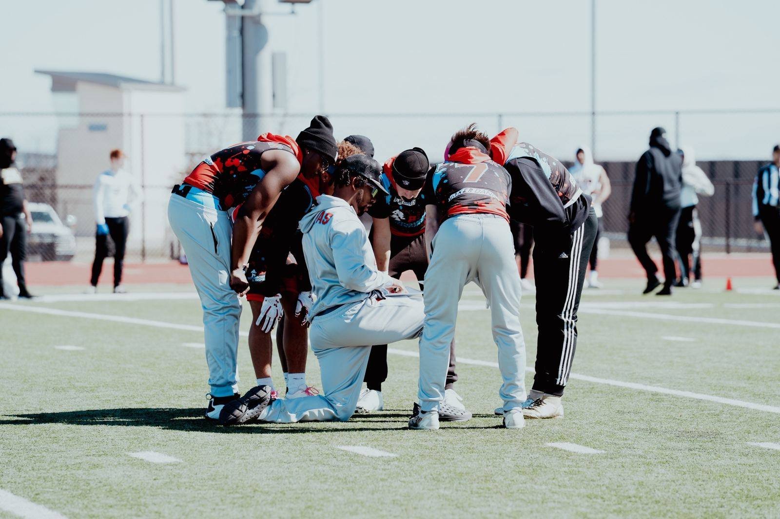 Coach kneeling with players in a sideline huddle